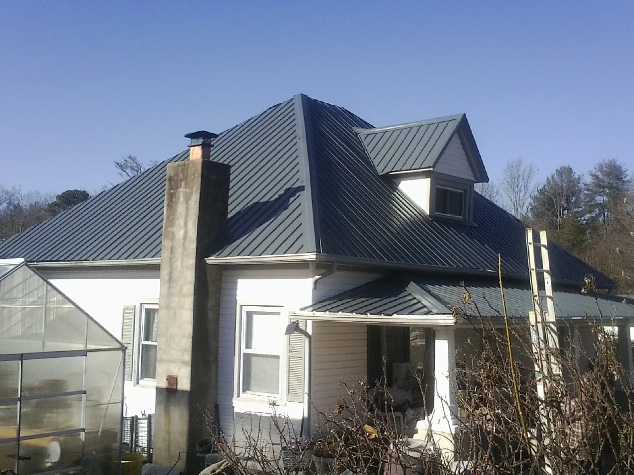 Dark blue standing seam metal roof on a white farmhouse with dormer — Slate & Tile Roof Repair by Roofing Brothers in New Bloomington