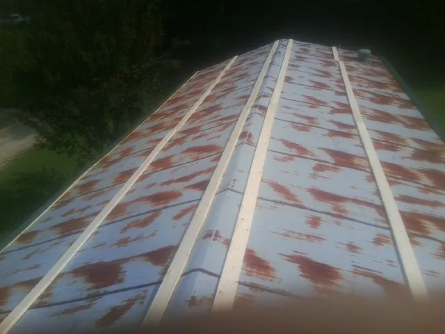 Rusted metal roof panels with new wood purlins before replacement — Storm Damage Roof Repair in New Bloomington by Roofing Brothers