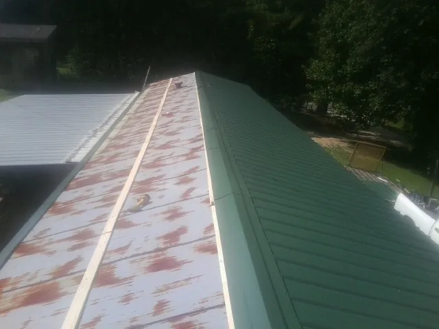 Old rusted panels beside newly installed green metal roofing — Wind Damage Roof Repair by Roofing Brothers in New Bloomington