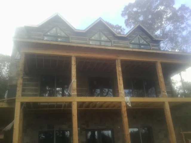 Dormers and porch framing on a large log home under construction — Roof Coating work by our crew in New Bloomington