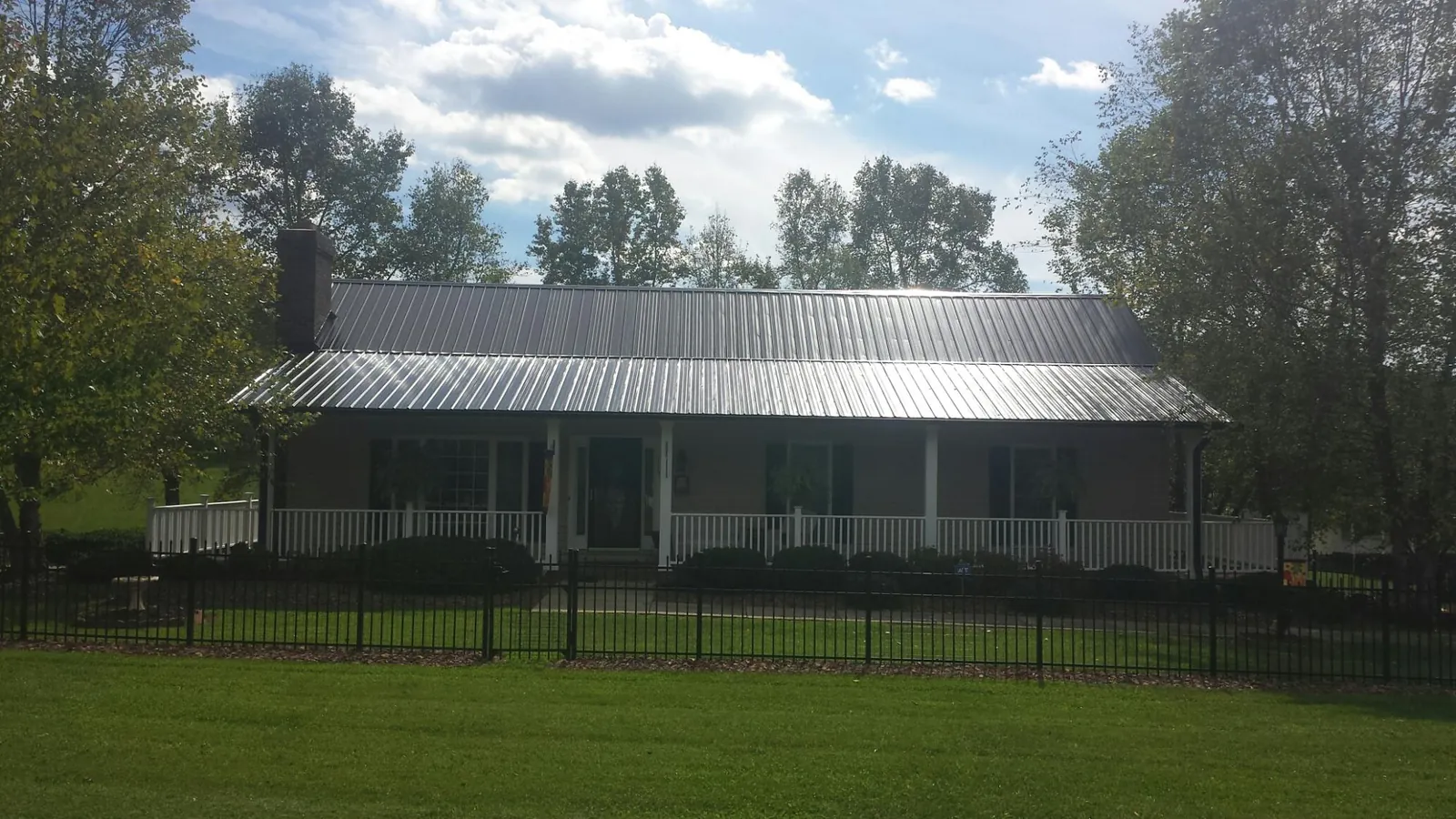 Gray metal roof on a brick ranch with a full width front porch — Gutter Guard Installation work by our crew in New Bloomington