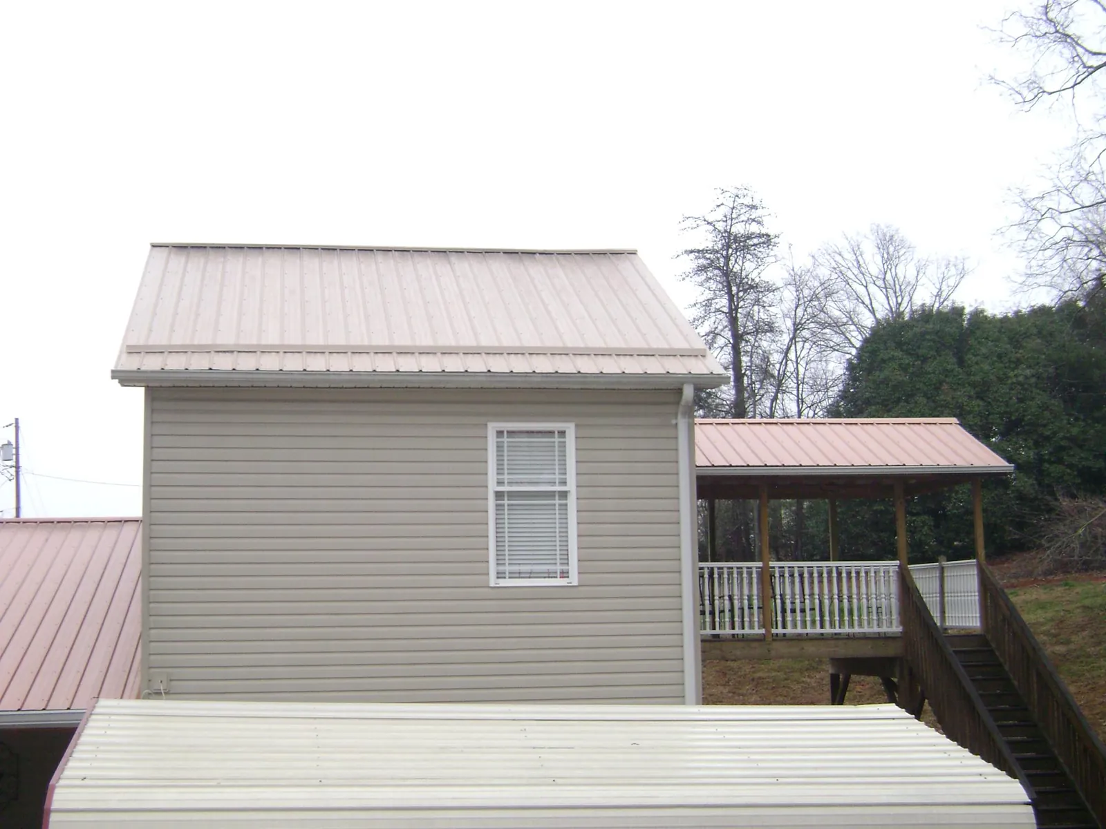 Tan metal roofs on a two story addition and attached porch, from a Roof Replacement job in New Bloomington