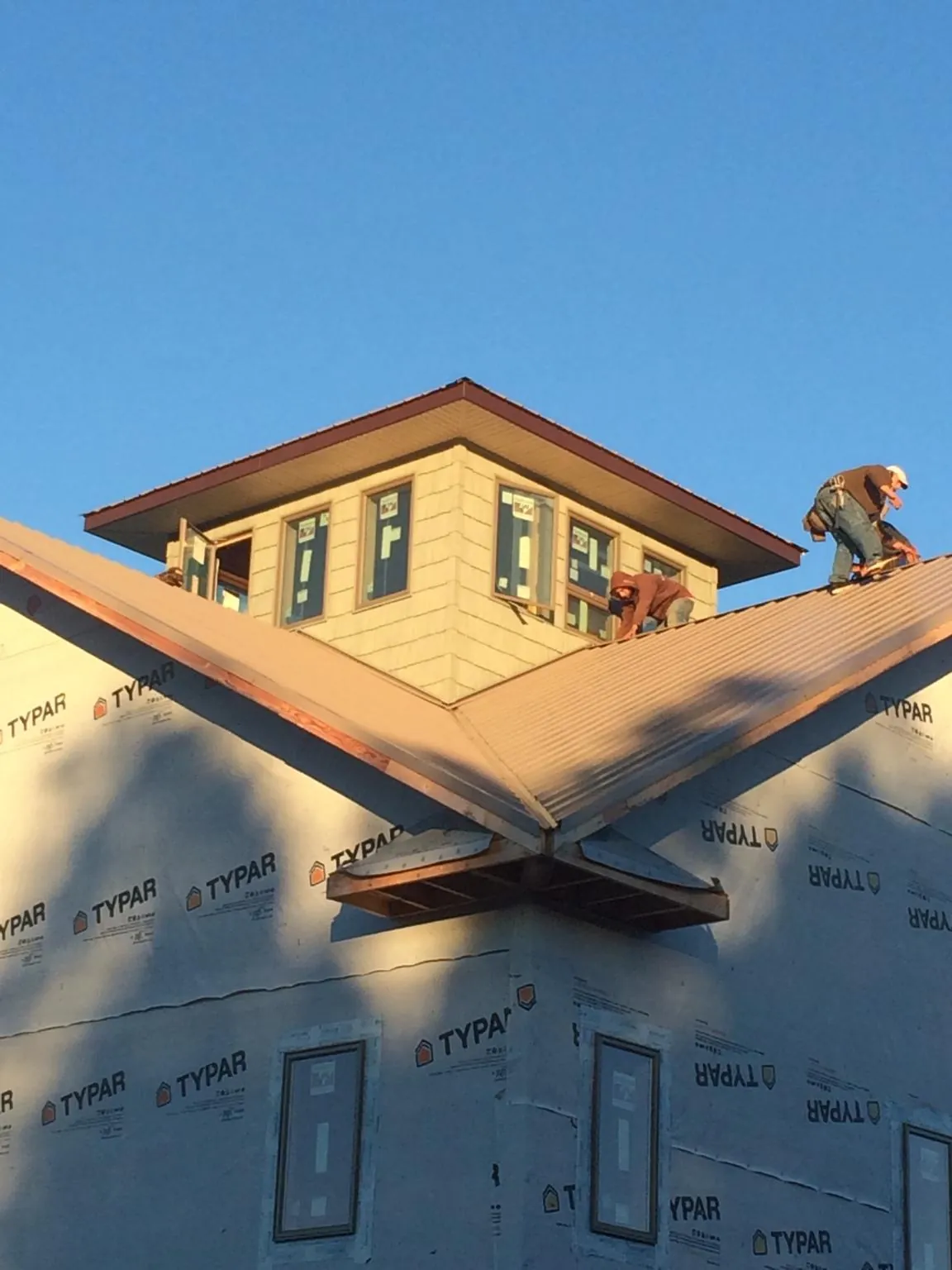 Roofers working around a rooftop cupola on a new metal roof at sunset — Roof Waterproofing in New Bloomington by Roofing Brothers
